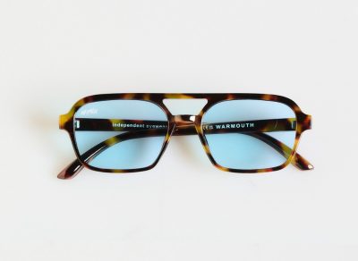 Presentamos las gafas de sol Gentleman Guy: un par de gafas de carey marrón con lentes tintadas en azul, ideales para el caballero exigente. Estas gafas de sol cuentan con una distintiva montura cuadrada, con la palabra "independent eyewear" y el texto "CEC WARMOUTH" elegantemente colocados en el interior de las patillas.